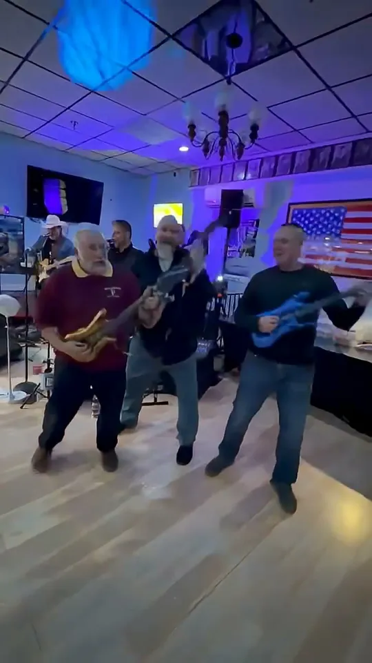 Straight A's band members playing electric guitars on a venue dance floor in front of an American flag