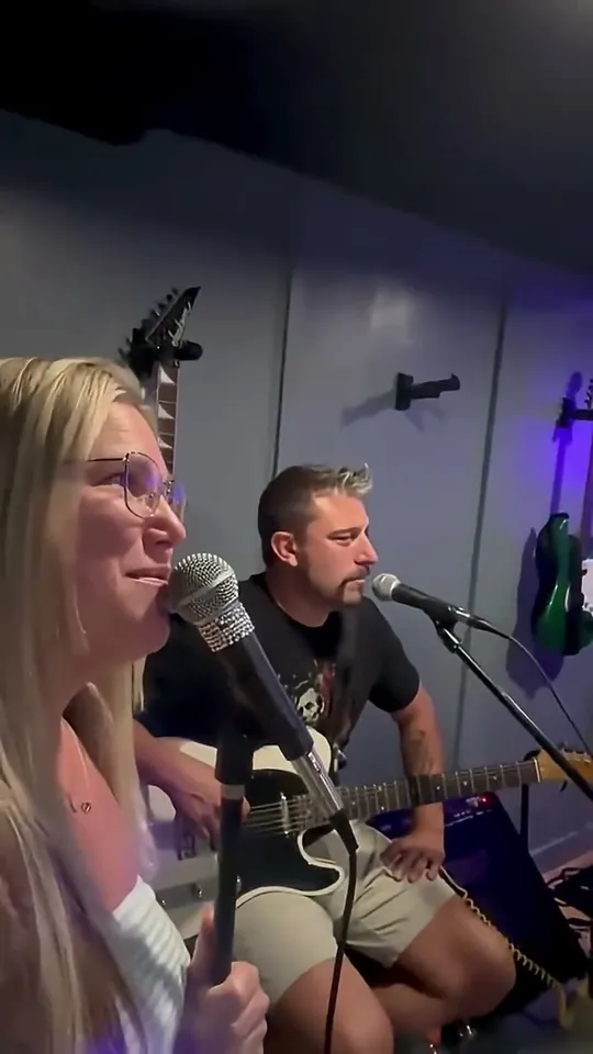 Straight A's band members rehearsing in a practice room with a bassist, guitarist, and drummer under blue neon lighting