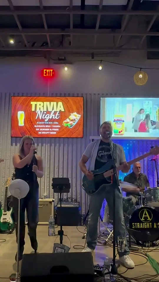 A Straight A's vocalist and guitarist performing live in front of a drummer with the Straight A's logo on the bass drum